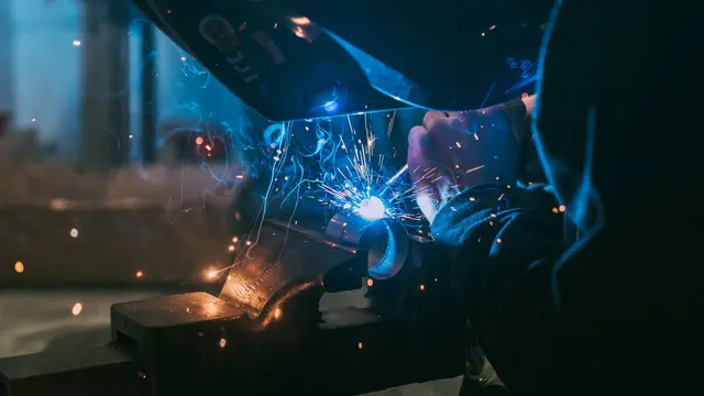 A welder working with sparks flying in a workshop
