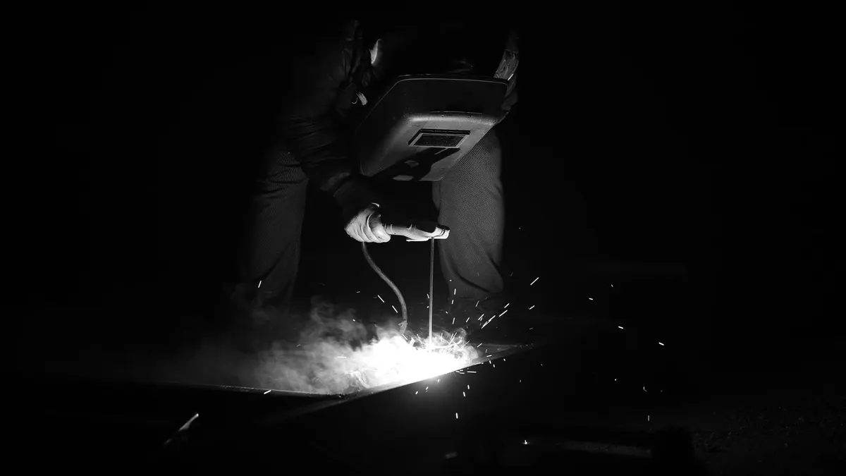 A welder working in the dark, lit only by the arc