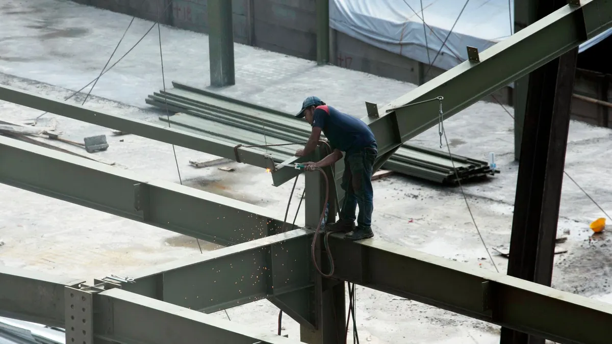 A construction worker welding steel beams on a building frame