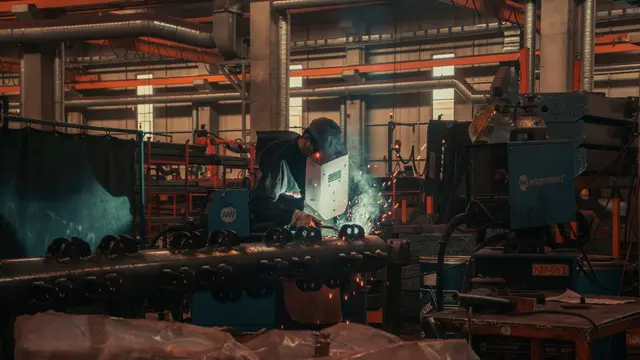 A welder working at a machine in a busy factory