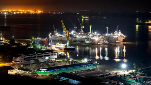 A shipyard port at night, with cranes and ships lit along the water