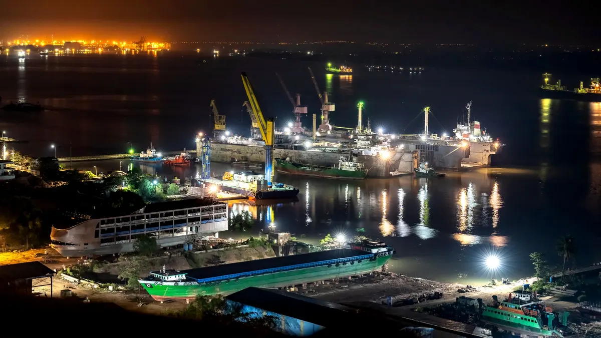 A shipyard port at night, with cranes and ships lit along the water