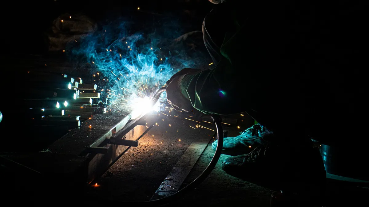 A welder's arc lighting up a dark workshop