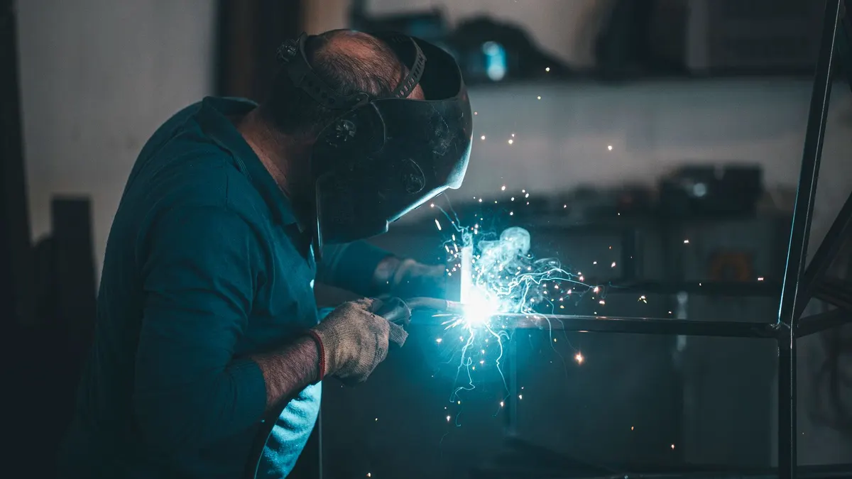 Close-up of a welder in a helmet running a bead in blue light